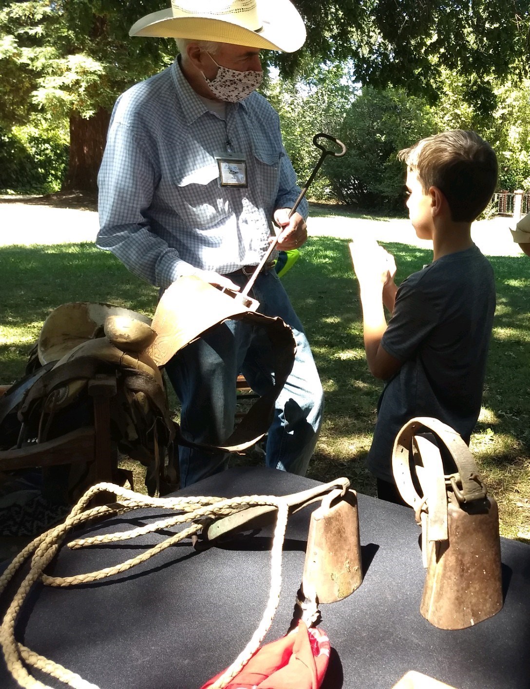 Paul sharing a branding iron and ranching tools with a camper during Camp Adobe.